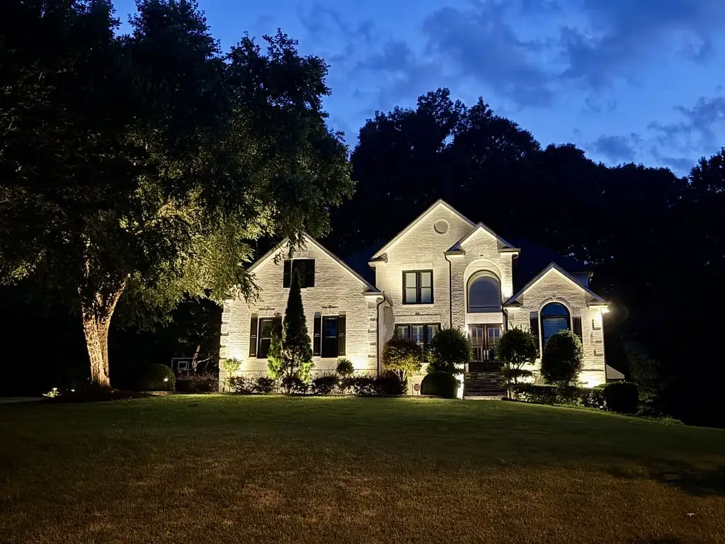 A modern white brick house illuminated by security lighting installation in Raleigh.